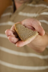 A man in a striped shirt holds out a loaf of bread to the camera.