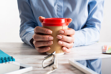 Office manager holding cardboard cup of coffee