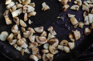 Raw mushrooms are fried in a pan.