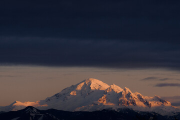 Snow covered mountain peak in winter as the clouds roll in just before sunset