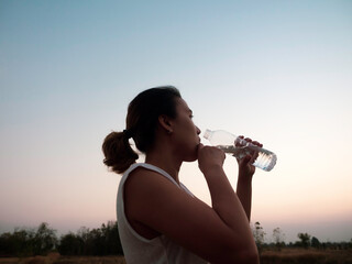 Asian woman drinking water after exercise.