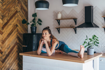 Flexible athletic woman sitting on a table at home