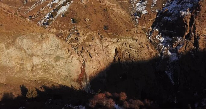 Panoramic wide view of mountain landscape with wild trees of juniper in a cold sunset time in winter in Alamut valley in Iran. cascade waterfall and river visible on a terrific cliff.