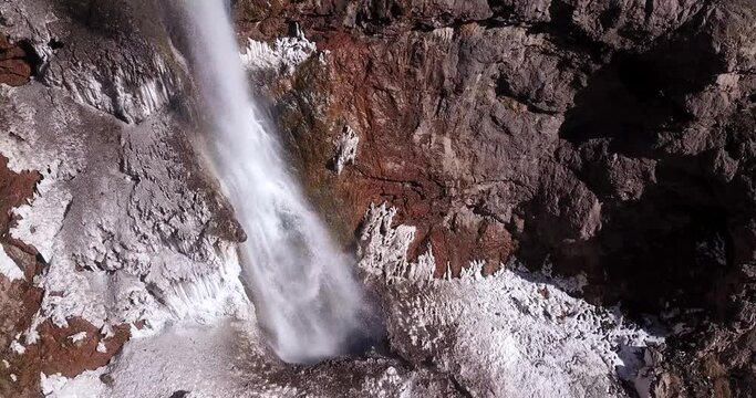 ice waterfall flow down heavily from a cliff on a snow covered ground in wild nature. snow like a salt in mountain. highlands of Alamut valley in Iran. travel to countryside for hiking in outdoor.