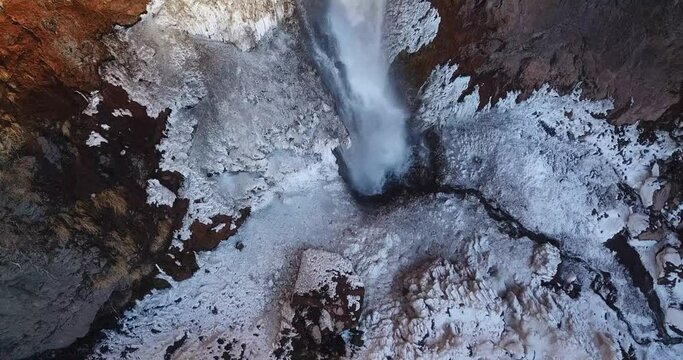 Birdseye view in flight over an ice fall in Iran. a river flow in a valley then fall from a cliff makes a waterfall in high mountains in Alamut rural area. Qazvin in central Iran with snow in winter.
