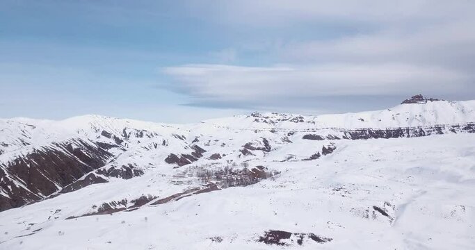 Flight over high Alborz mountain village in winter snow beautiful white landscape. Aerial scenic view of Piche Bon village Alamut Valley Qazvin Mazandaran border in Iran. little town wooden cottage.