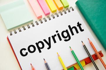 the word copyright is written on a white notepad which lies on a white background near a green notepad and stickers