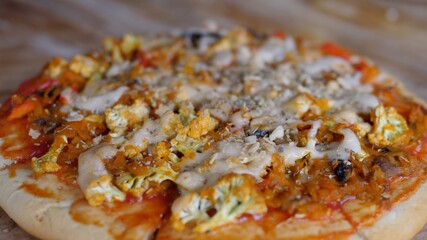 Hand serving vegan pizza with vegetables and vegan cheese on the wooden table. Healthy vegan lifestyle