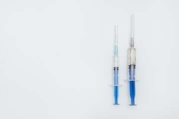 Two syringes with different dose of medicine or vaccine on white or gray background with a place...