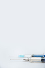Two syringes with a different dose of medicine or vaccine on a white or gray background with a...