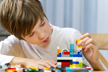 young boy playing with plastic construction toys at home.