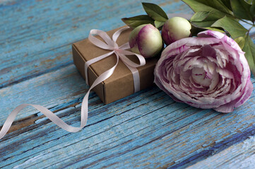 gift box, pink peonies on blue wooden background