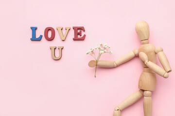 Wooden mannequin with flowers and words LOVE U on color background