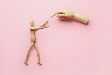 Wooden mannequin and hand on color background