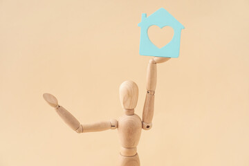 Wooden mannequin with figure of house on color background