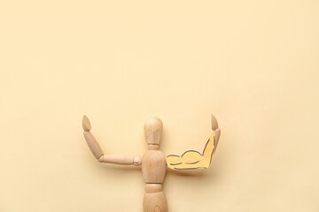 Wooden mannequin with drawn muscular arm on color background