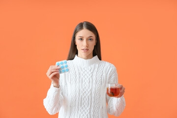 Sick young woman with tea and pills on color background