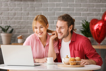 Young couple with laptop celebrating Valentine's Day at home