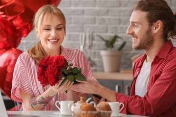 Young man greeting his girlfriend on Valentine's Day at home