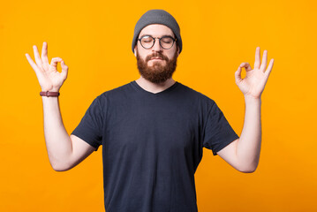 A young hipster is staying calm and relaxed in a zen positioin .