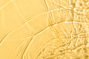 Transparent and clean yellow water background with sunlight reflection