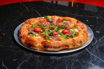 A Pepperoni pizza on black marble table background. Traditional Italian cuisine concept.