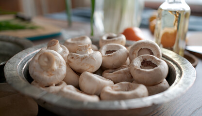 Champignon mushrooms on the table. Home kitchen. Sunny day. Close up. Soft focus in the background