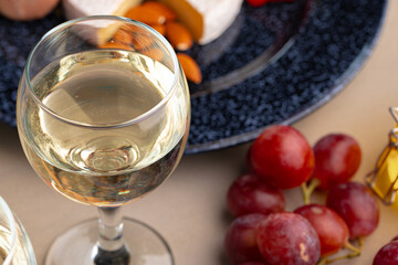 Glass of wine and piece of cheese on table close up