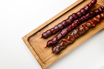 Churchkhela served on a wooden board over white background. Traditional Georgian dessert, Georgian cuisine concept.