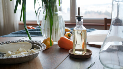 Kitchen table with ingredients for cooking. Still life. Cheese, olive oil, sweet peppers. Sunny day. Soft focus in the background