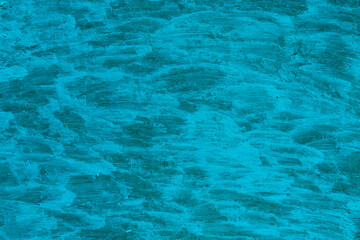 Blue background with a greenish tint from the surface painted with acrylic paints. The surface is painted over with brush strokes. Texture of acrylic paint strokes.