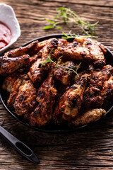 Chicken wings barbeque in a cast iron baking dish with BBQ sauce and rosemary