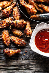 Chicken wings barbeque in a cast iron baking dish with BBQ - Top of view