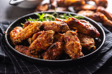 Chicken wings barbeque in a cast iron baking dish with BBQ sauce and rosemary