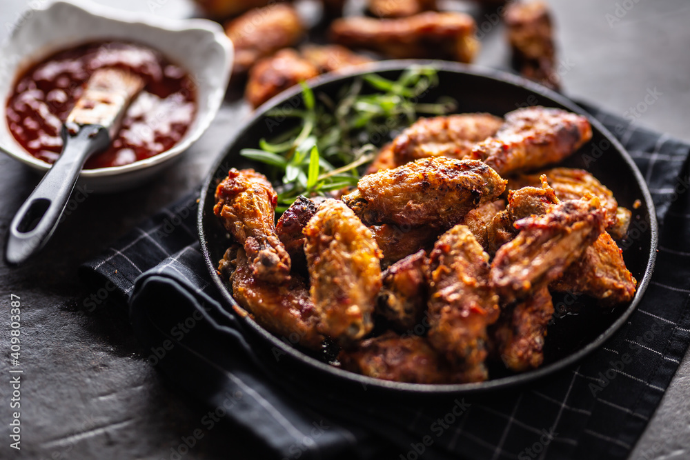 Wall mural chicken wings barbeque in a cast iron baking dish with bbq sauce and rosemary