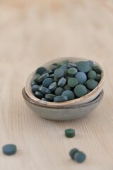 Spirulina algae green in tablets in round  cups on a light wooden shabby background..Dietary supplements.Super food. Healthy organic seaweed.Healthy lifestyle. Food product.Dry algae tablets 