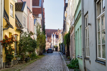 Fototapeta na wymiar Beautiful cozy courtyard with old houses and flowers in the street of old town Lubeck, Germany