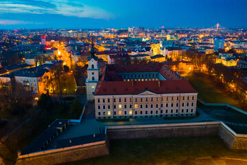 Aerial view of Renaissance building of Rzeszow castle on background of lighted cityscape at twilight, Poland