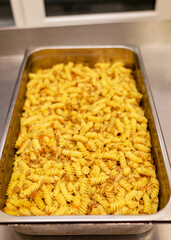 boiled pasta with meat and toppings in a metal pan, cooking