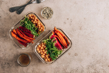 Vegan healthy meal prep containers. Chickpeas, sweet potatoes, arugula, radish, avocado and sauce for lunch on concrete background. Vegan, healthy, detox food concept. Top view