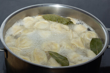 Homemade dumplings are boiled in a saucepan with boiling water. Close-up