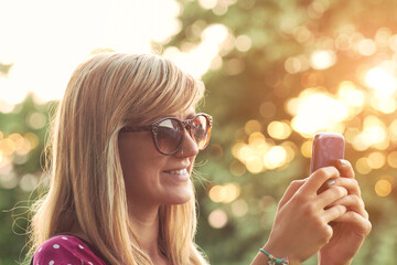 Young woman using modern smartphone outdoors.