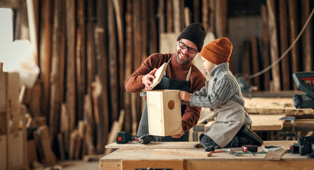 Dad and kid assembling wooden bird house - obrazy, fototapety, plakaty
