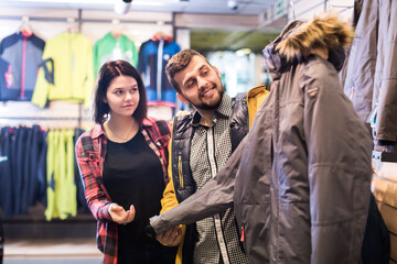 Guy and woman choosing a new windcheater in sports clothes store