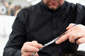 Male client getting haircut by hairdresser with comb and scissors