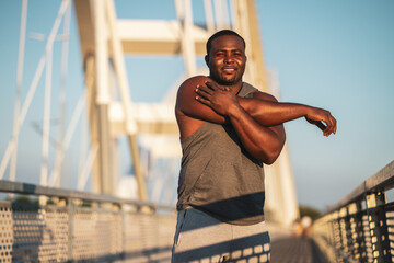 Portrait of young african-american man in sports clothing who is exercising to reduce his body weight. 
                        
