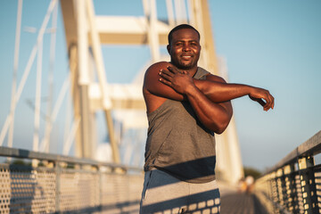 Portrait of young african-american man in sports clothing who is exercising to reduce his body weight. 
