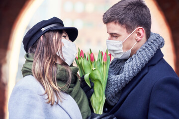 Happy couple celebrating Valentines Day in masks during covid-19 pandemic