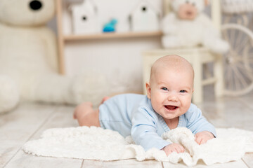 laughing baby lies at home in the children's room with toys, development concept and games