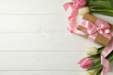 Beautiful tulips and gift box on white wooden background